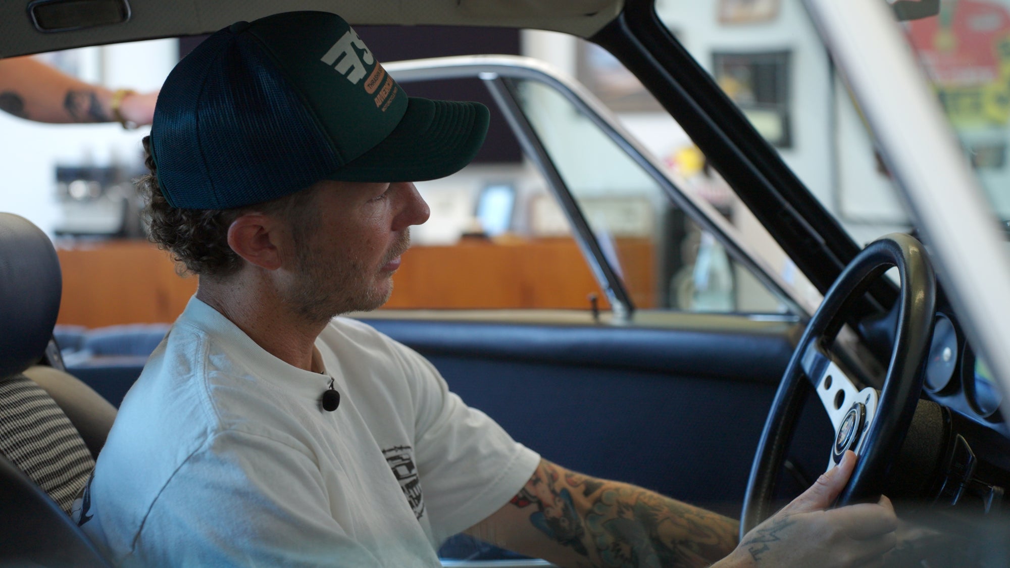 Lance Coury behind the wheel of a vintage car in his private garage